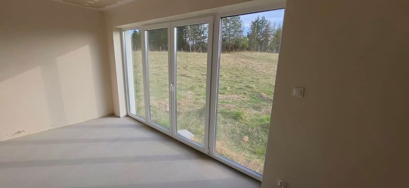 Salon z dużym przeszkleniem i widokiem na łąki